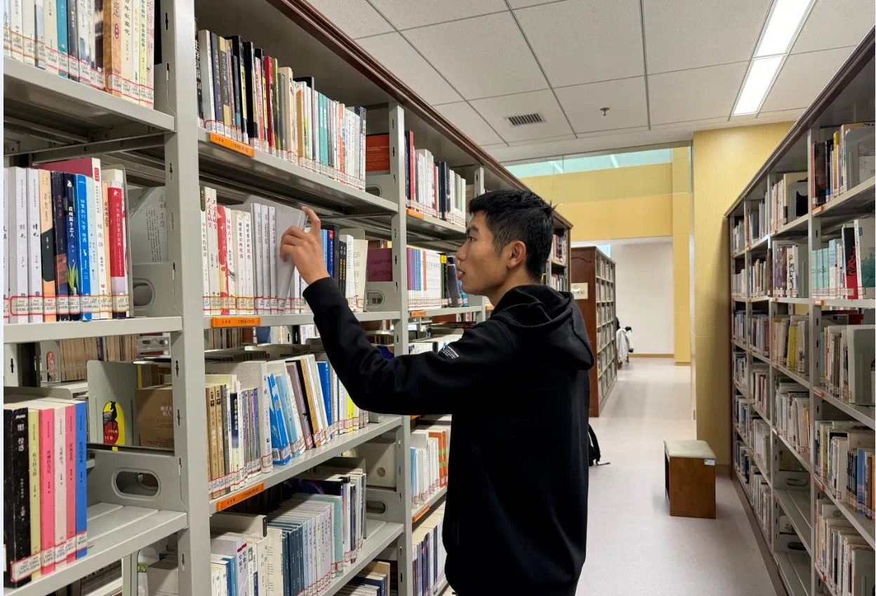 Student browsing books inside Xinjiang Medical University Library