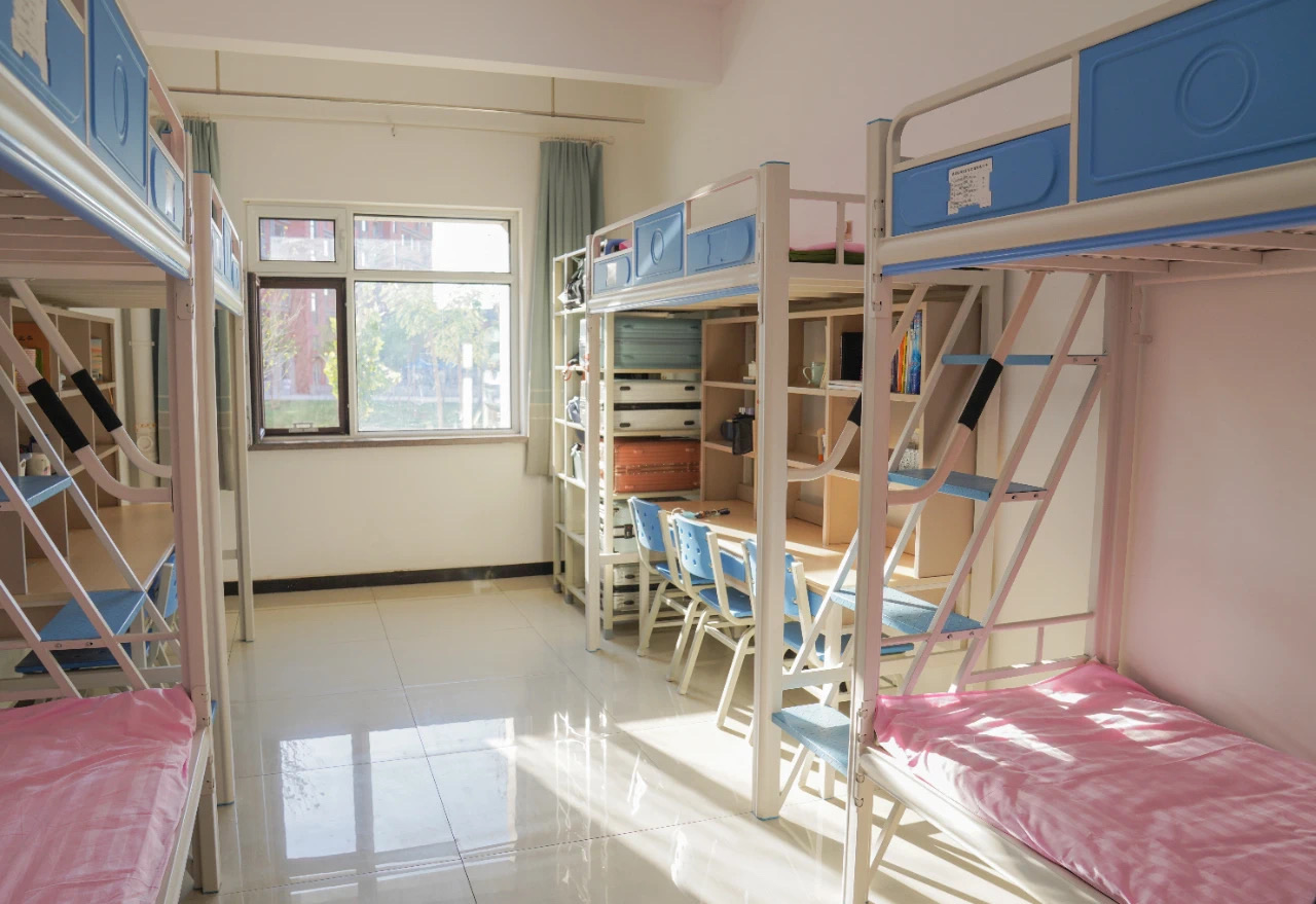 Shared student dormitory room with beds and study desks at Xinjiang Medical University